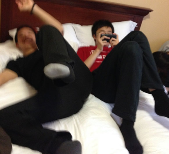 Jerry was bouncing off the bed and Tony was playing on his phone while waiting for the next competition. (left to right)
